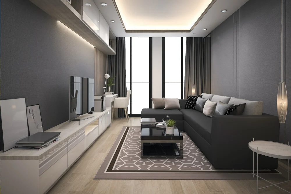 Ein modernes Wohnzimmer einer Wohnung in Münster mit einem großen schwarzen Sektionssofa, einem geometrisch gemusterten Teppich, einem Flachbildfernseher auf einer schlichten weißen Konsole und einem kleinen runden Beistelltisch. Das Objekt wurde vermittelt durch Rosenke Immobilien in Münster.